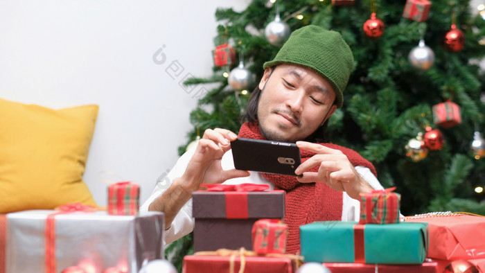 年轻的亚洲男人。微笑而采取照片圣诞节现在礼物盒子快乐亚洲博主照片和记录视频博客圣诞节礼物和饰品庆祝活动聚会，派对