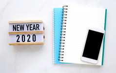 新一年木盒子空白笔记本纸和聪明的电话与空白屏幕白色大理石表格背景新一年模拟模板与复制空间为文本前视图