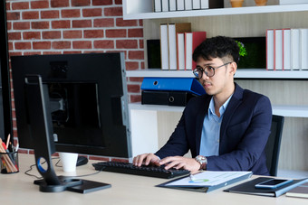 年轻的亚洲办公室男人。斗争与电脑沮丧亚洲业务男人。看电脑而工作办公室业务人斗争与技术