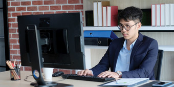 年轻的亚洲办公室男人。斗争与电脑沮丧亚洲业务男人。看电脑而工作办公室业务人斗争与技术横幅