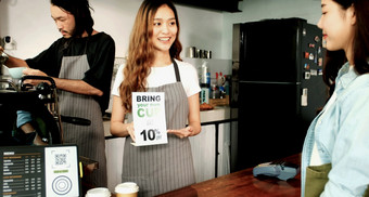 带你的自己的杯得到折扣年轻的亚洲女人咖啡师女服务员介绍零浪费促销活动亚洲女孩客户咖啡商店咖啡馆