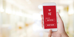 促销代码移动电话屏幕为购物在线折扣手持有智能手机得到出售凭证在模糊商店背景与复制空间数字市场营销商务