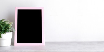 空粉红色的木框架站在白色水泥墙和黑色的大理石地板上与影子背景复制空间为模拟和模板