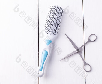 美容剪刀和按摩梳子采取从以上白色木背景美容剪刀和按摩梳子采取从以上