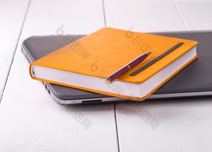 橙色笔记本与铅笔说谎移动PC在木背景橙色笔记本与铅笔说谎移动PC