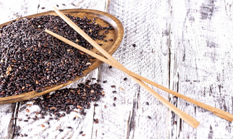 黑色的大米和筷子木板老木背景的黑色的大米和筷子木板老木背景