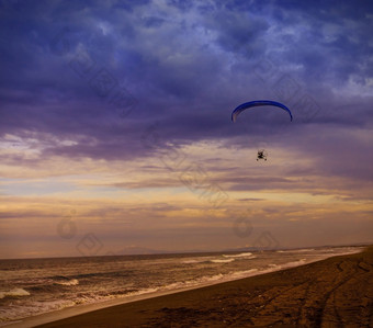 轮廓动力滑翔伞飙升的飞行在的海对日落天空的轮廓动力滑翔伞飙升的飞行在的海对日落天空