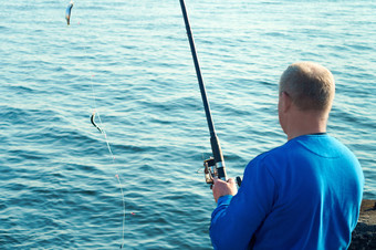 男人。抓住了鱼钓鱼杆钓鱼白痴钓鱼的晚上海钓鱼的春天
