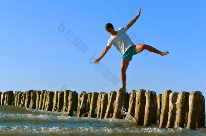 年轻的男人。站的防浪堤木防浪堤防浪堤的海为保护从的风暴木防浪堤年轻的男人。站的防浪堤防浪堤的海为保护从的风暴