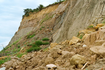 陡峭的海海岸粘土杂草丛生的坡不同的土壤的倒塌岩石粘土杂草丛生的坡不同的土壤的倒塌岩石陡峭的海海岸