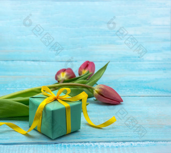 礼物和郁金香木背景春天花和礼物盒子红色的郁金香和绿色包装春天花和礼物盒子红色的郁金香和绿色包装