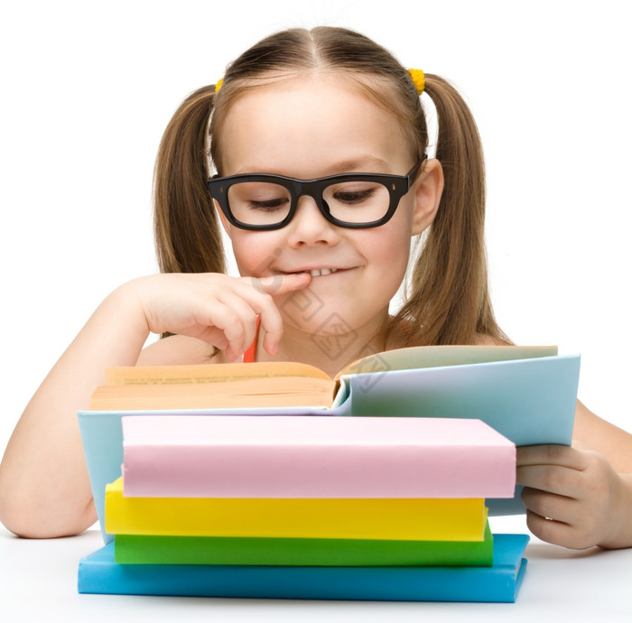 的小女孩阅读书穿眼镜孤立的在图片