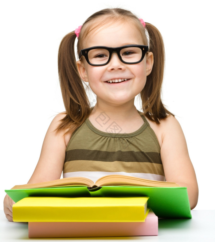 的快乐的小女孩阅读书而穿眼镜孤立的在图片
