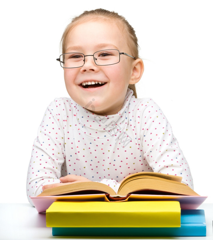 的快乐的小女孩阅读书而穿眼镜孤立的在图片