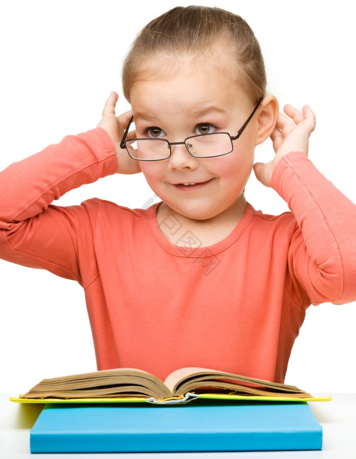 的快乐的小女孩阅读书穿眼镜孤立的在图片