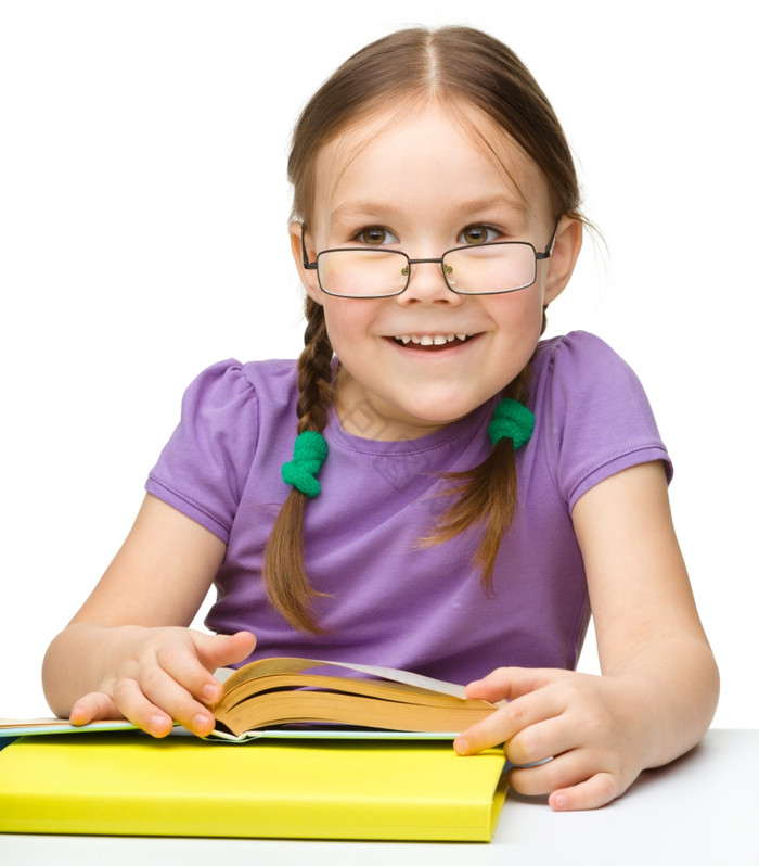 的快乐的小女孩阅读书穿眼镜孤立的在图片