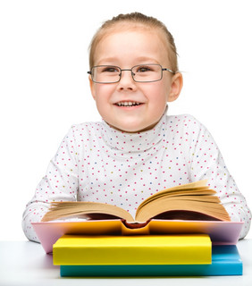 的快乐的小女孩阅读书而穿眼镜孤立的在