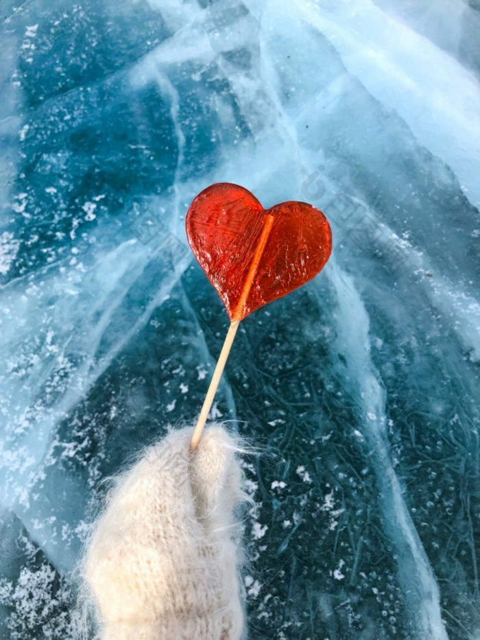 红色的棒棒糖的形状心持有手手套对的背景冰红色的棒棒糖的形状心持有手手套对的背景冰