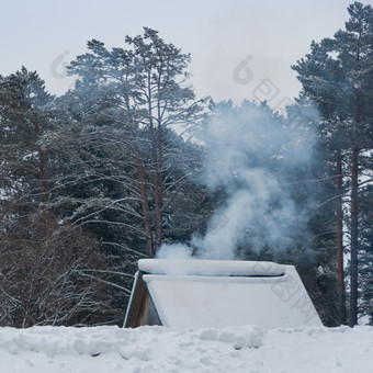 烟从的烟囱雪覆盖屋顶房子
