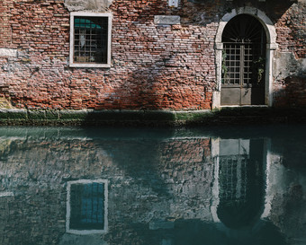 外观部分长满青苔的老砖房子与木古董通过狭窄的运河威尼斯意大利外观部分长满青苔的老砖房子与木古董通过狭窄的运河威尼斯意大利