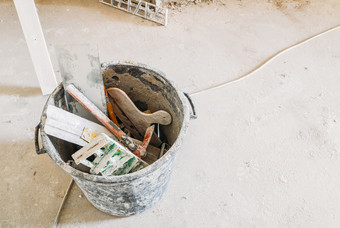 老工具为建设覆盖油漆坐着尘土飞扬的地板上桶铲子水泥统治者和垃圾老工具为建设覆盖油漆坐着尘土飞扬的地板上
