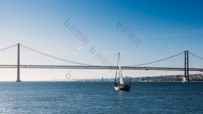 帆船与白色帆的塔霍河河4月桥里斯本葡萄牙帆船与白色帆的塔霍河河4月桥里斯本葡萄牙