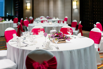 婚礼接待晚餐表格装饰与玫瑰兰花花与氨纶白色封面椅子红色的透明硬纱腰带大丝带