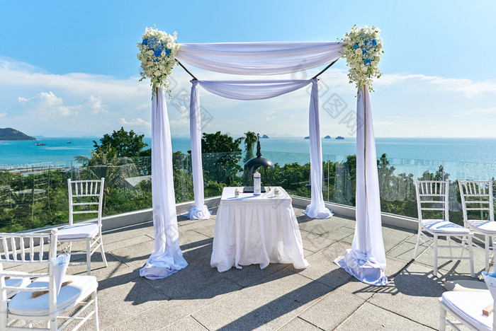 的婚礼聚会地点设置的山与全景海洋视图白色拉奥椅子与锥玫瑰花瓣的拱和坛白色装饰与最小的玫瑰花寒岛泰国