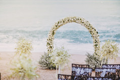 的美丽的婚礼聚会地点设置与花花装饰拱与全景海洋视图背景