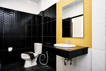 标准设施通用的厕所。。。房间小酒店公寓装饰与光滑的陶瓷黑色的和黄色的墙与冲洗厕所。。。<strong>水</strong>槽毛巾架和<strong>脸盆</strong>为玻璃镜子