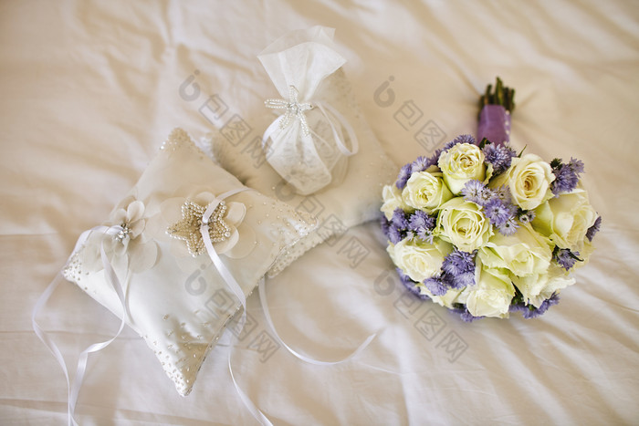 柔和的花束与玫瑰和紫罗兰色的花装饰为的新娘和缓冲为婚礼环的床上