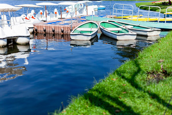 小绿色玻璃纤维<strong>船</strong>和一些<strong>天鹅船</strong>浮动的蓝色的湖水的码头的公共公园曼谷城市生活为家庭和朋友放松时间