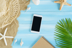 前视图智能手机海稻草他请注意书叶子和海贝壳的海沙子蓝色的木背景夏天概念空蓝色的木地板上