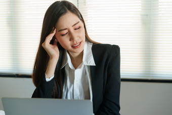 亚洲业务女人有压力的工作与电脑为<strong>长时间</strong>办公室并发症状概念