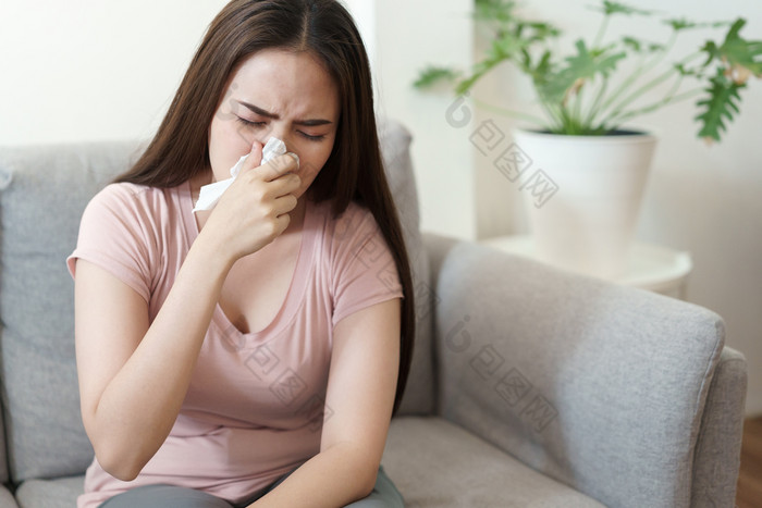 亚洲可爱的女孩有流感季节与打喷嚏使用纸组织坐着沙发首页健康和疾病概念