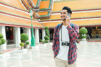 亚洲男人。旅游走说话聪明的电话和微笑什么suthat提普拉拉姆ratchaworawihan曼谷泰国的夏天时间只有旅行和背包客概念