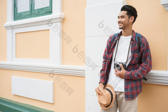 英俊的亚洲男人。旅游站墙而持有稻草他景点曼谷泰国只有旅行和背包客概念