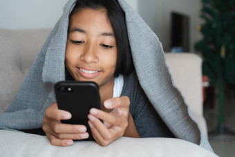 亚洲孩子女孩是看视频那是在开玩笑在线媒体的小女孩使用的智能手机看视频为娱乐沙发首页