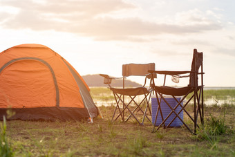 野营帐篷营帐篷和椅子的河日落的夏天生活方式概念和野营假期