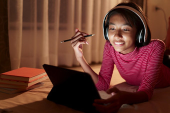 快乐亚洲女孩研究视频会议在线与老师的平板电脑的卧室晚上亚洲孩子看和教育距离的电脑概念学习首页