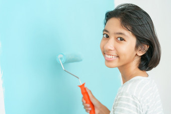 女孩亚洲绘画墙与的油漆辊特写镜头手年轻的孩子改造装修的室内首页与的颜色蓝色的特写镜头孩子快乐微笑的脸