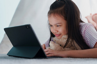 亚洲小女孩使用平板电脑帐篷首页晚上亚洲孩子打字工作数字电脑