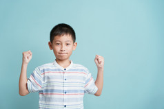 快乐亚洲小男孩站蓝色的背景孤立的肖像可爱的男人。成功幸福和微笑