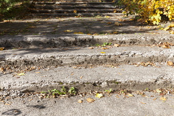 老混凝土楼梯覆盖与下降叶子的秋天季节有很多损害的楼梯自己老混凝土楼梯