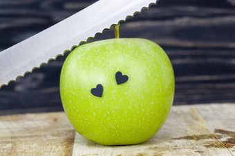 成熟的美味的绿色苹果黑色的董事会对的背景黑色的墙特写镜头水果但的苹果是几黑色的心<strong>贴纸金属</strong>刀绿色苹果和心