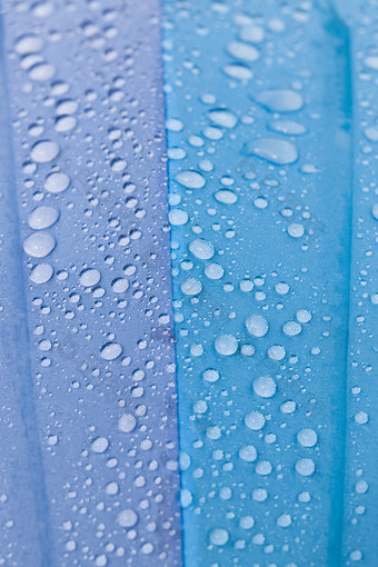 五彩缤纷的蓝色的紫色的雨与水滴后的最后的雨特写镜头在户外的蓝色的材料