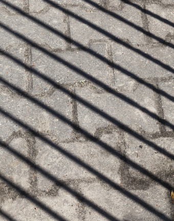 行人路瓷砖哪一个瀑布的影子附近的栅栏的条纹部分阳光和阴影路影子