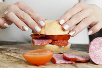 烹饪三明治首页从的通常面包片香肠和番茄蔬菜使女人特写镜头烹饪三明治首页