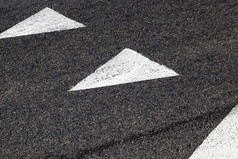 白色路标记的形式白色箭头画黑色的沥青表明的方向运动汽车特写镜头白色路标记