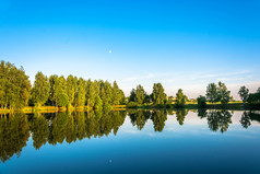 小湖安静的夏天晚上与的反射树和的月亮的水
